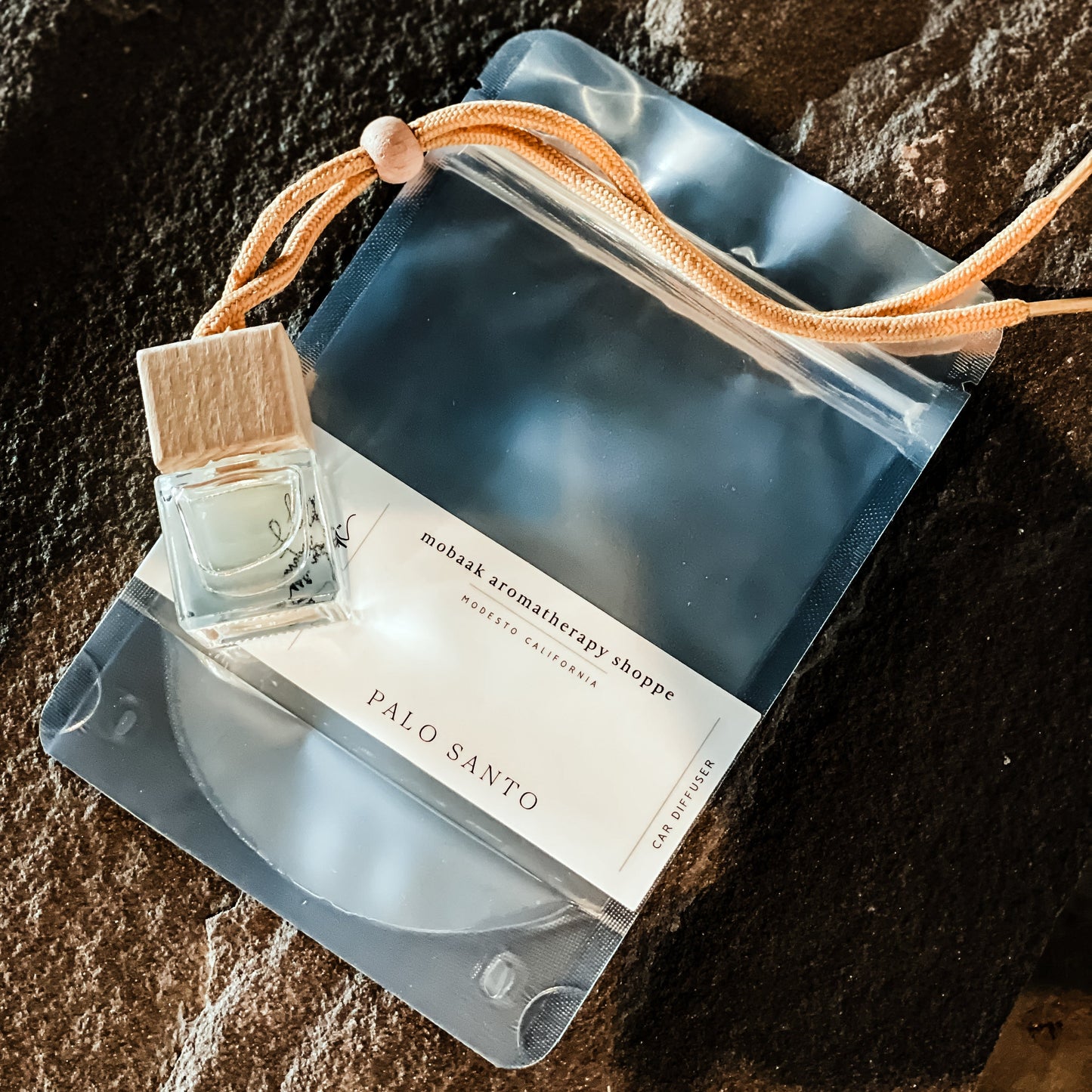 Natural car scent diffuser bottle with wooden cap, product bag, and hanging braid